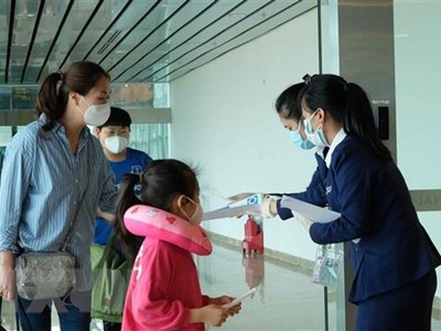 Nhân viên Sân bay quốc tế Cam Ranh phát tờ rơi hướng dẫn phòng dich COVID-19 cho hành khách tại khu vực nhập cảnh. (Ảnh: Nguyễn Dũng/TTXVN).