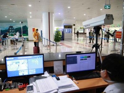 Lực lượng y tế kiểm tra thân nhiệt đối với hành khách nhập cảnh. (Ảnh: Doãn Tấn/TTXVN).
