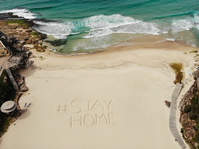 Lời kêu gọi ở nhà để tuân thủ quy định giãn cách xã hội được viết trên một bãi biển ở Sydney. Nguồn Getty.