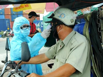 Nhân viên y tế đo thân nhiệt người ra vào thành phố Hồ Chí Minh tại chốt kiểm dịch. (Ảnh: Đinh Hằng/TTXVN).