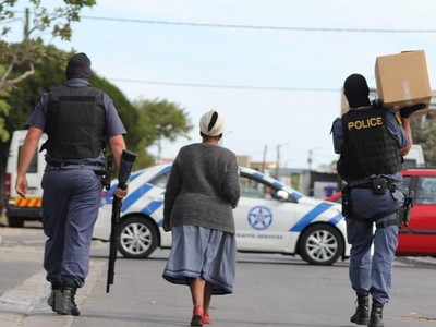 Cảnh sát Nam Phi mang hàng hóa cho một cụ già trên đường đi chợ về. (Ảnh: TTXVN phát).