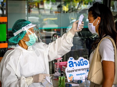 Nhân viên y tế kiểm tra thân nhiệt phòng lây nhiễm COVID-19 tại Bangkok,Thái Lan. (Ảnh: AFP/TTXVN).