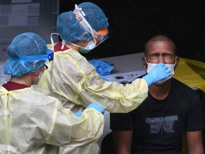 Nhân viên y tế xét nghiệm một lao động nhập cư tại Singapore ngày 27/4. Ảnh: AFP.