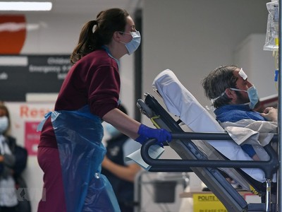 Nhân viên y tế chuyển bệnh nhân nhiễm COVID-19 tới bệnh viện ở London, Anh. (Ảnh: AFP/TTXVN).