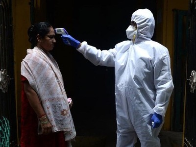 Một bác sĩ kiểm tra thân nhiệt cho người dân tại nơi cư trú ở thành phố Chennai, Ấn Độ, hôm 29/6. Ảnh: AFP.