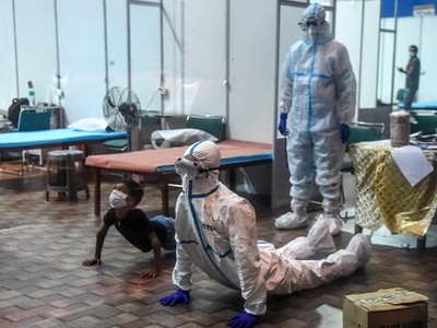 Nhân viên y tế và một bệnh nhân Covid-19 nhỏ tuổi thực hiện động tác yoga tại một bệnh viện Ấn Độ. Ảnh: AFP.