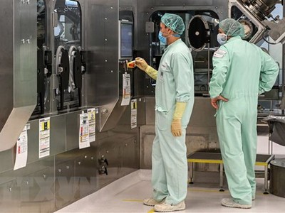 Các kỹ thuật viên giám sát việc sản xuất quy mô lớn và cung ứng vắcxin phòng COVID-19. (Ảnh: AFP/TTXVN).