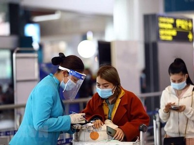 Nhân viên của hãng hàng không hướng dẫn khách làm thủ tục khai báo y tế trước khi vào điểm soi chiếu để lên tàu bay. (Ảnh: Huy Hùng/TTXVN).