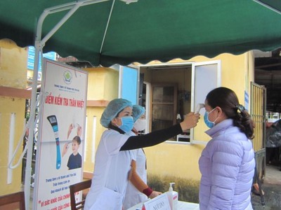 Cán bộ Trung tâm Y tế thành phố Yên Bái kiểm tra thân nhiệt cho bệnh nhân đến khám tại đơn vị (Ảnh: KT).