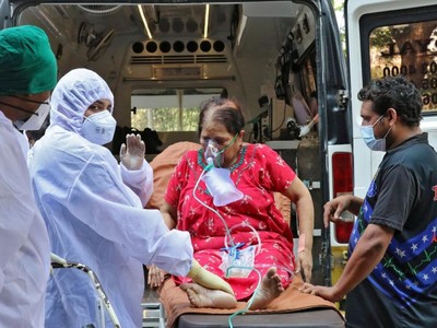 Nhân viên y tế và người thân bế một phụ nữ từ xe cấp cứu đến cơ sở điều trị Covid-19, ở Mumbai, Ấn Độ. Ảnh: Reuters.
