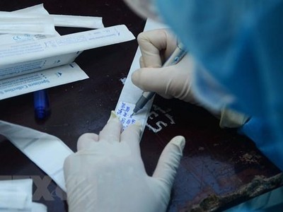 Nhân viên y tế ghi thông tin người dân vào mẫu xét nghiệm. (Ảnh: Văn Dũng/TTXVN).