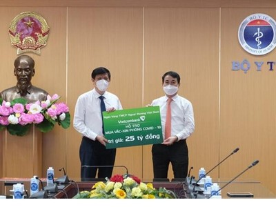 Đại diện Vietcombank, đ/c Nghiêm Xuân Thành – UV BCH TW Đảng, Uỷ viên BTV Đảng ủy khối DNTW, Bí thư Đảng ủy, Chủ tịch HĐQT Vietcombank (bên phải) trao biển tượng trưng số tiền 25 tỷ đồng hỗ trợ Bộ Y tế mua vắc xin phòng COVID-19 cho GS.TS. Nguyễn Thanh Long - UV BCH TW Đảng, Bộ trưởng Bộ Y tế.