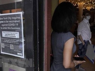 Bảng yêu cầu trình chứng nhận đã tiêm vaccine ngừa COVID-19 đối với thực khách bên ngoài một nhà hàng ở New York (Mỹ). (Ảnh: AFP/TTXVN).