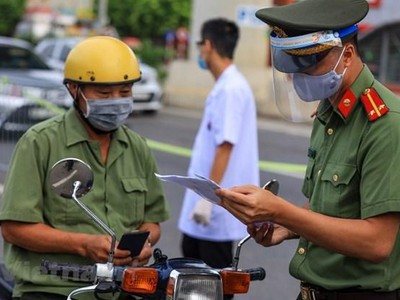 Trên tuyến đường Cầu Diễn (Bắc Từ Liêm, Hà Nội), lực lượng chức năng đã lập hàng rào chia thành 2 làn đường để tiến hành kiểm soát. Ngày hôm nay, Tổ công tác sẽ tiến hành tuyên truyền cho người dân về quy định mới trong Chỉ thị 20 đã áp dụng để chống dịch. (Ảnh: Minh Sơn/Vietnam+).