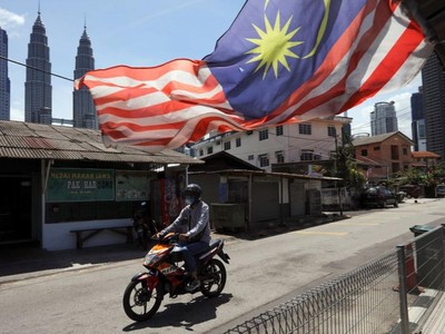 Một người đàn ông đeo khẩu trang lái xe máy trên đường phố Kuala Lumpur, Malaysia ngày 2/2/2021. Ảnh: Reuters.