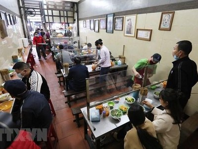 Quán ăn trong nhà lắp tấm chắn giữa các vị trí ngồi đảm bảo phòng chống dịch. (Ảnh: Thành Đạt/TTXVN).