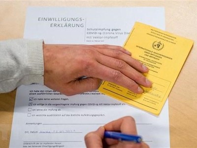 Người dân điền thông tin vào bản khai bên thẻ Chứng nhận tiêm vaccine ngừa COVID-19 do Tổ chức Y tế Thế giới (WHO) cấp phép, tại điểm tiêm chủng ở Halle/Saale, miền Đông Đức. (Ảnh minh họa: AFP/TTXVN).