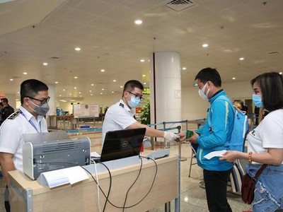 Nhân viên y tế kiểm tra phiếu khai báo y tế của hành khách trước khi làm thủ tục nhập cảnh tại cửa khẩu Sân bay quốc tế Nội Bài (Ảnh: TTXVN).