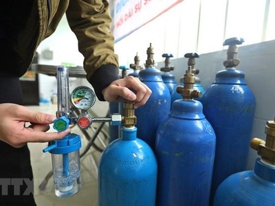 Thành viên Tổ hỗ trợ theo dõi người nhiễm COVID-19 tại nhà phường Lĩnh Nam kiểm tra bình oxy trước khi mang đến hỗ trợ F0 cách ly y tế, điều trị tại nhà. (Ảnh: Minh Quyết/TTXVN).