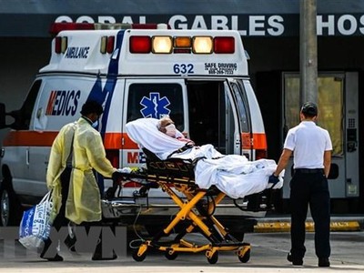 Nhân viên y tế chuyển bệnh nhân COVID-19 tới bệnh viện ở Coral Gables, gần Miami, Mỹ. (Ảnh: AFP/TTXVN).