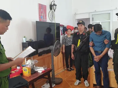 Phạm Trung Kiên (áo xanh than) nghe đọc lệnh khám xét khẩn cấp tại nhà riêng (Ảnh: PX03 Điện Biên).