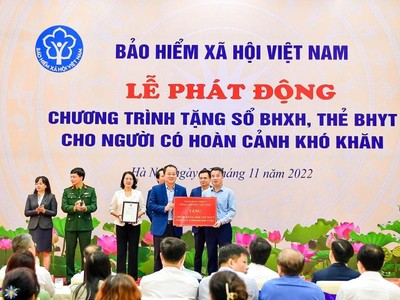 Phó Tổng Giám đốc Vietcombank Nguyễn Việt Cường (hàng đầu, bên trái) trao biểu trưng tặng 1.000 sổ BHXH, 9.968 thẻ BHYT với tổng trị giá 5 tỷ đồng cho đại diện BHXH Việt Nam.