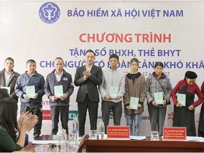 Phó Chủ tịch chuyên trách HĐQL BHXH Nguyễn Văn Cường trao tặng sổ BHXH, thẻ BHYT tới người dân.