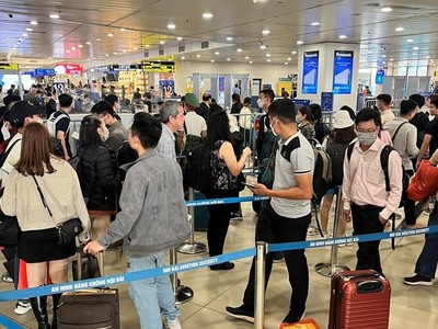Hành khách xếp hàng dài chờ vào khu vực kiểm tra giấy tờ tùy thân và soi chiếu an ninh tại sân bay Nội Bài. (Ảnh: CTV/Vietnam+).