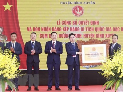 Lãnh đạo huyện Bình Xuyên (bên trái) nhận quyết định và Bằng xếp hạng di tích quốc gia đặc biệt Cụm đình Hương Canh. (Ảnh: Hoàng Hùng/TTXVN).