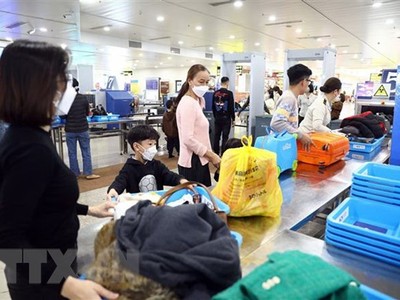 Hành khách xếp đồ để qua máy soi chiếu tại Cảng hàng không quốc tế Nội Bài. (Ảnh: Huy Hùng/TTXVN)