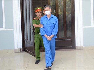 Cơ quan chức năng dẫn giải cựu Giám đốc CDC Đà Nẵng ra xe sau khi kết thúc phiên tòa sáng 25/8. (Ảnh: Văn Dũng/TTXVN)