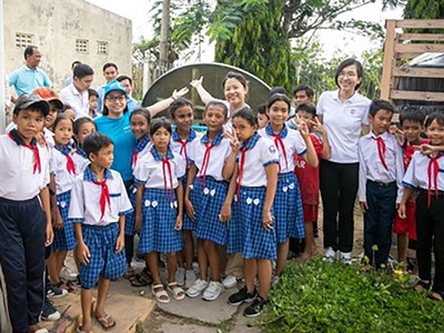 Chị Nguyễn Hồng Hạnh, cán bộ Nước sạch, Vệ sinh môi trường - UNICEF Việt Nam (áo xanh, bên trái) và cán bộ Masterise Group chia sẻ niềm vui với các em học sinh trường Tiểu học Long Phú C khi đón thiết bị nhà vệ sinh không phát thải. Ảnh: UNICEF Việt Nam/Trương Việt Hùng.