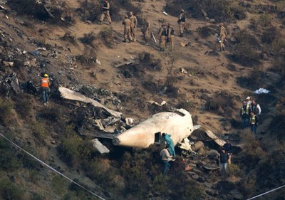 Các nhà điều tra Pakistan kiểm tra hiện trường máy bay rơi hôm qua. Ảnh: AP