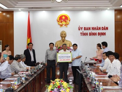 Bộ trưởng Nguyễn Chí Dũng trao số tiền ủng hộ nhân dân bị thiệt hại do lũ lụt cho lãnh đạo tỉnh Bình Định