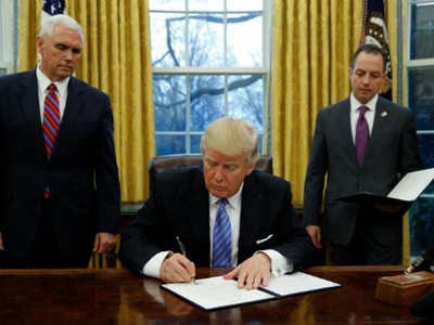  Ông Trump ký sắc lệnhhành pháp (executive order)dưới sự chứng kiến của Phó tổng thống - Mike Pence (trái) và Chánh Văn phòng Nhà Trắng -Reince Priebustại Phòng Bầu dụcngày 23/1 (theo giờ Washington). Ảnh:Reuters