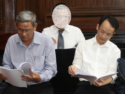 Bị cáo Lê Văn Thanh (bên trái) và Nguyễn Thanh Chương (bên phải) đang xem lại tại liệu trước khi xét xử. (ảnh Lê Toàn)