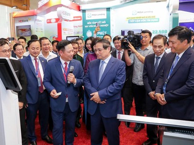 Thủ tướng Chính phủ Phạm Minh Chính thăm và lắng nghe ông Hoàng Minh Ngọc, Phó tổng giám đốc Agribank giới thiệu về hoạt động số của Agribank.