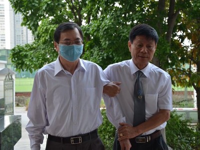 Ông Vũ Huy Hoàng được luật sư dìu đến tòa. 