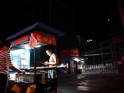 Một người bán đồ ăn trước lối vào một khu công nghiệp ở thành phố Đông Quan, tỉnh Quảng Đông, Trung Quốc - nơi bị ảnh hưởng bởi thiếu điện. Ảnh: AFP