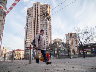 Một người phụ đi bên dưới một tòa nhà bị hư hại do giao tranh ở Ukraine. Ảnh: AFP