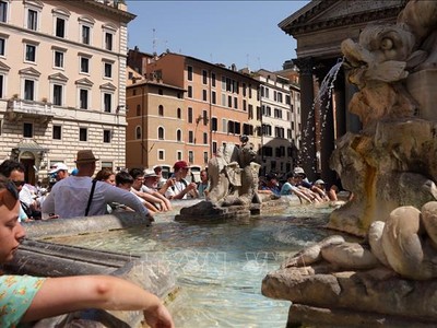 Khách du lịch tránh nóng bên đài phun nước tại Rome, Italy, ngày 18/7/2023. Ảnh: THX/TTXVN
