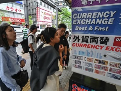 Người dân đứng bên ngoài quầy đổi tiền để xem tỷ giá đồng yên so với ngoại tệ, dọc con phố ở trung tâm Tokyo vào ngày 29/4/2024. Ảnh: AFP
