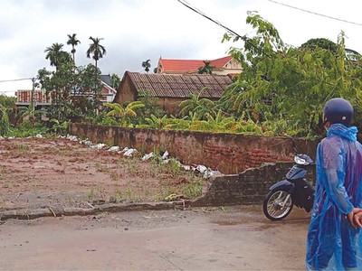 Một nhà đầu tư đội mưa để đi xem đất tại huyện Chương Mỹ. (Ảnh: Vũ Thanh)