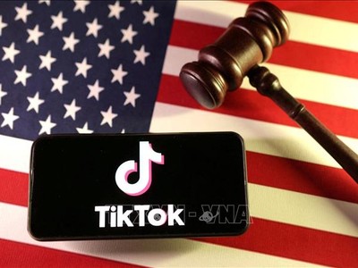 Logo của ứng dụng TikTok trên điện thoại và quốc kỳ Mỹ. Ảnh: Reuters/TTXVN