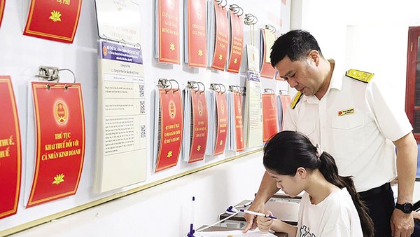 Cán bộ thuế hướng dẫn người dân làm thủ tục hành chính thuế. Ảnh: Dũng Minh 