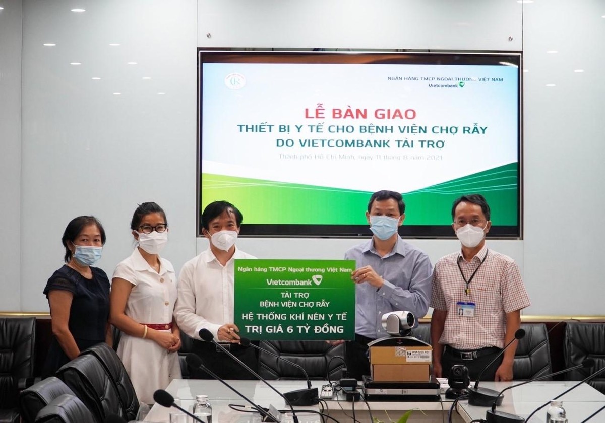Ông Đặng Hoài Đức, Phó tổng giám đốc Vietcombank (thứ 3 từ trái sang) trao biểu trưng tặng quà cho đại diện Bệnh viện Chợ Rẫy, thầy thuốc ưu tú, Bác sĩ CKII Nguyễn Tri Thức (thứ 2 từ phải sang) – Giám đốc Bệnh viện