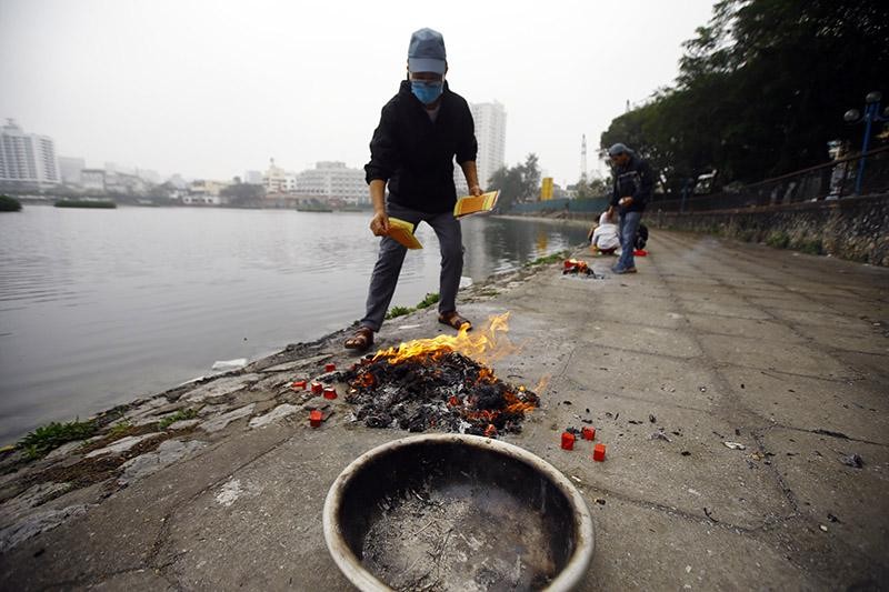 Người lớn tuổi thì cẩn thận hơn khi mang theo cả thau để đốt vàng mã, nhưng do số lượng vàng mã nhiều nên cũng để ra mép hồ rồi đốt Người lớn tuổi thì cẩn thận hơn khi mang theo cả thau để đốt vàng mã, nhưng do số lượng vàng mã nhiều nên cũng để ra mép hồ rồi đốt