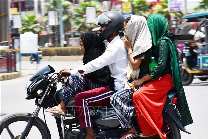Người dân quấn khăn che mặt để tránh nóng khi di chuyển ngoài trời tại Prayagraj, Ấn Độ ngày 20/6/2024. Ảnh: ANI/TTXVN