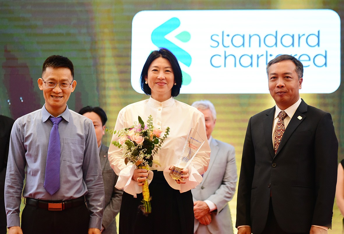 Ông Lê Trọng Minh (phải), Tổng Biên tập Báo Đầu tư và ông Trần Quốc Trung (phải), Phó vụ trưởng Vụ Quản lý khu kinh tế (Bộ Kế hoạch và Đầu tư), trao kỷ niệm chương vinh danh cho các doanh nghiệp. Trong ảnh, đại diện Ngân hàng Standard Chartered Việt Nam nhận cúp vinh danh.