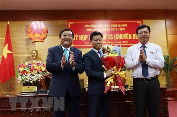 Tân Phó Bí thư Tỉnh ủy, Chủ tịch Ủy ban Nhân dân tỉnh Cà Mau Lê Quân nhận hoa chúc mừng từ Bí thư Tỉnh ủy Nguyễn Tiến Hải và Chủ tịch Hội đồng Nhân dân tỉnh Trần Văn Hiện. (Ảnh: Kim Há/TTXVN).